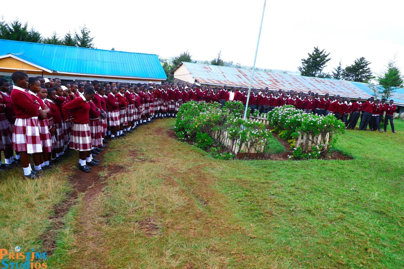 Students in maroon uniform lined up for morning assembly around the flag pole